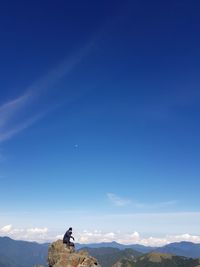 Man on mountain against blue sky