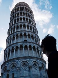 Low angle view of man standing by leaning tower of pisa