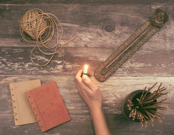 High angle view of person hand holding lit candles on table