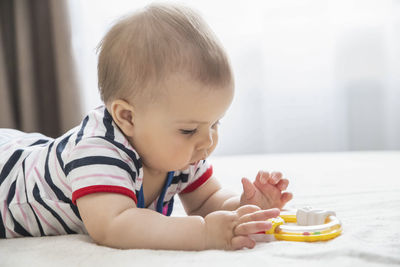 Portrait of cute boy playing with toy blocks on bed at home