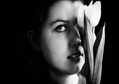 Close-up portrait of woman against black background