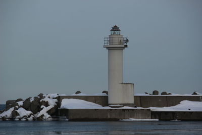 Lighthouse by sea against sky