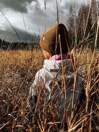 Rear view of woman wearing hat on field against sky