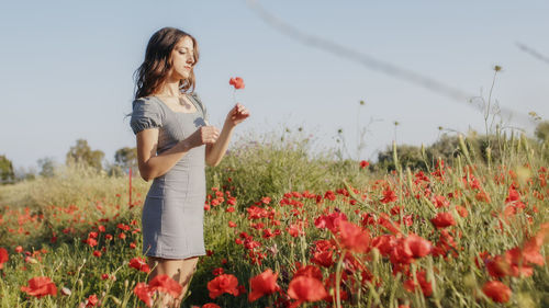 Young woman standing amidst flowering plants on field