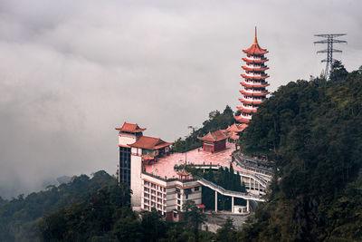Low angle view of buddhist temple and trees against sky in a jungle at genting highland, malaysia