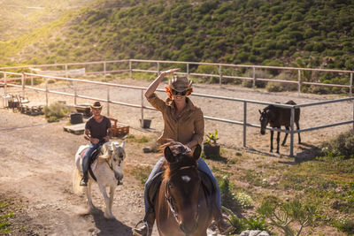 Friends riding horses on dirt road