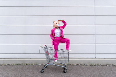 Full length of woman sitting against pink wall