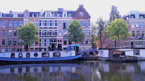 Boats moored in river by buildings in city