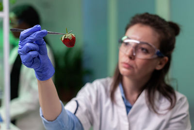Scientist holding strawberry with tweezers