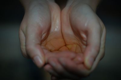 Close-up of hands clasped with water