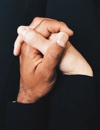 Close-up of couple holding hands against black background
