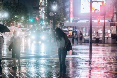 Rear view of people on city street at night