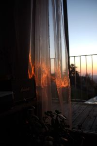 Close-up of fire against window at sunset