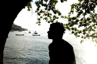 Silhouette man looking at sea against sky