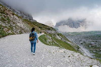 Rear view of man standing on rocks against mountain