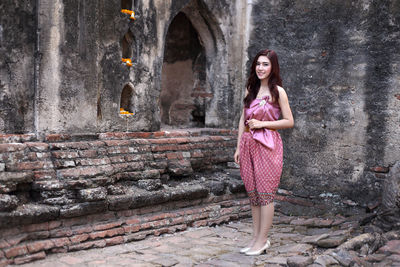 Portrait of woman standing against stone wall