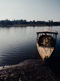 Boat moored on lake against sky