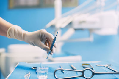 Cropped hand of dentist picking dental equipment on table