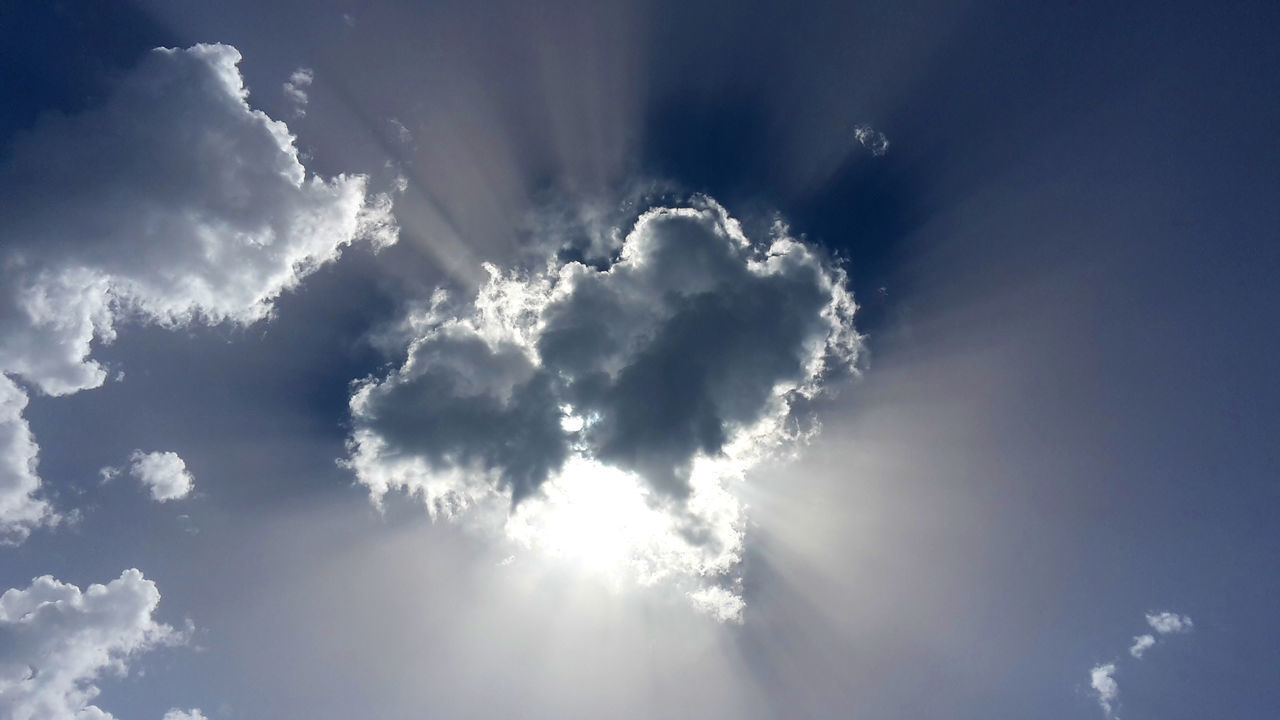 LOW ANGLE VIEW OF SUN STREAMING THROUGH CLOUDS