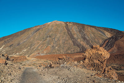 Scenic view of arid landscape against clear blue sky