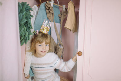 Portrait of cute girl standing at entrance of home