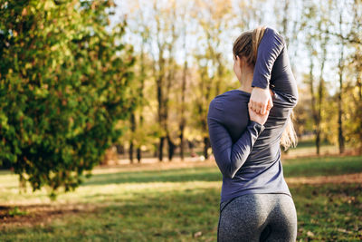 Slender girl from the back holds hands in the castle, training in nature.