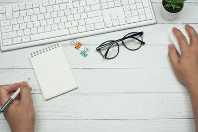 Midsection of person holding paper with text on table