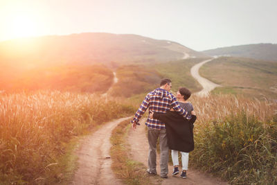 Rear view full length of couple walking on mountain road