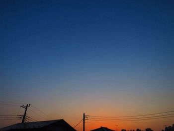 Low angle view of silhouette electricity pylon against clear sky