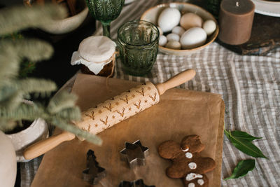 A smiling gingerbread man with sugar, spices and a patterned rolling pin on parchment. kitchen table