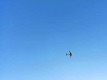 Low angle view of airplane against clear blue sky