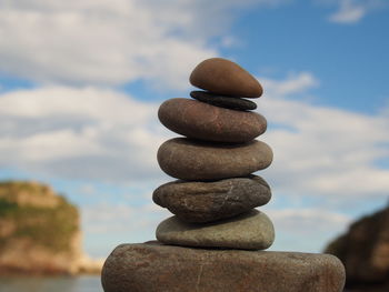 Stack of pebbles on rock against sky