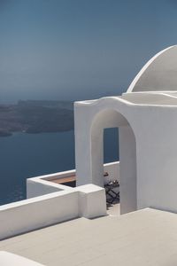 Whitewashed building by sea against sky during sunny day