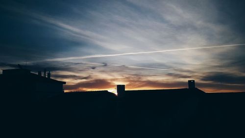 Silhouette of vapor trails in sky at sunset
