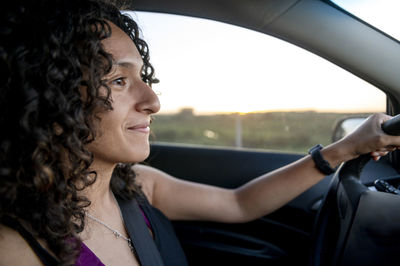 Happy woman smiling while driving a car on the road.