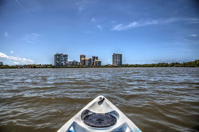 Boat in sea by buildings against sky