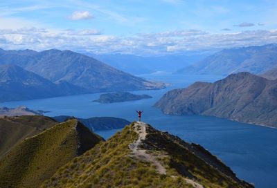 Rear view of man standing on mountain against sky