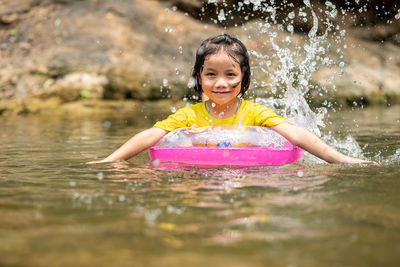 Portrait of smiling girl with inflatable ring swimming in lake