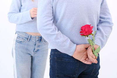 Young attractive man holding a rose behind his back to surprise his lover.