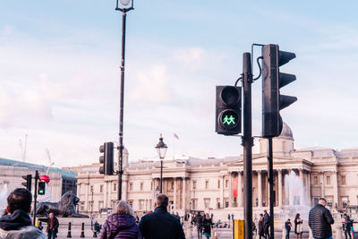 Street photo of traffic light with two green man holding hand in hand, with a heart between them. 