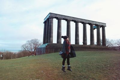 Full length of woman standing on grass against sky