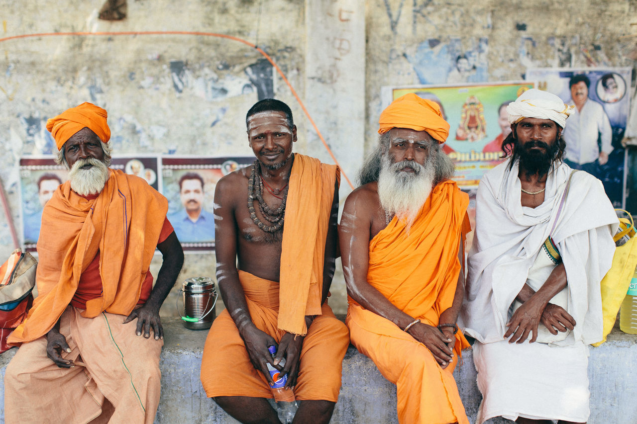 group of people, men, real people, religion, adult, people, orange color, clothing, belief, males, traditional clothing, day, mature adult, looking at camera, front view, spirituality, mature men, architecture, wall - building feature