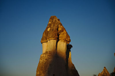 Low angle view of rock formation against clear blue sky