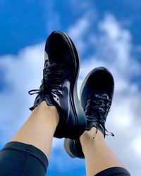 Low section of woman wearing shoes against sky