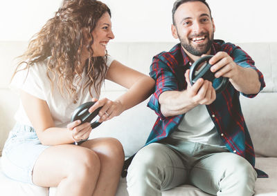 Couple playing video game while siting on sofa at home