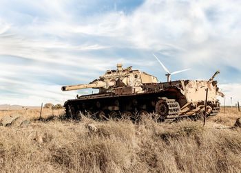 Abandoned vehicle on field against sky