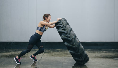 Full length of woman exercising with tire