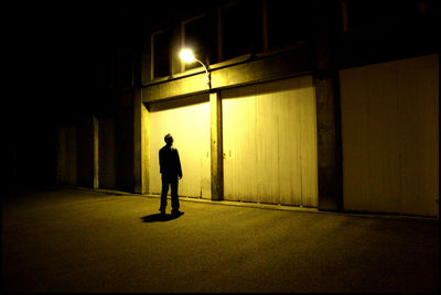 Full length of man standing by illuminated building at night