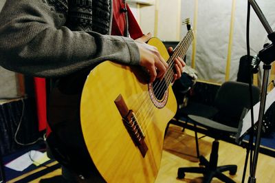 Midsection of man playing guitar