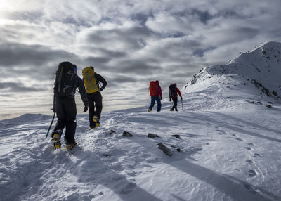 Rear view of people walking on snow covered mountain